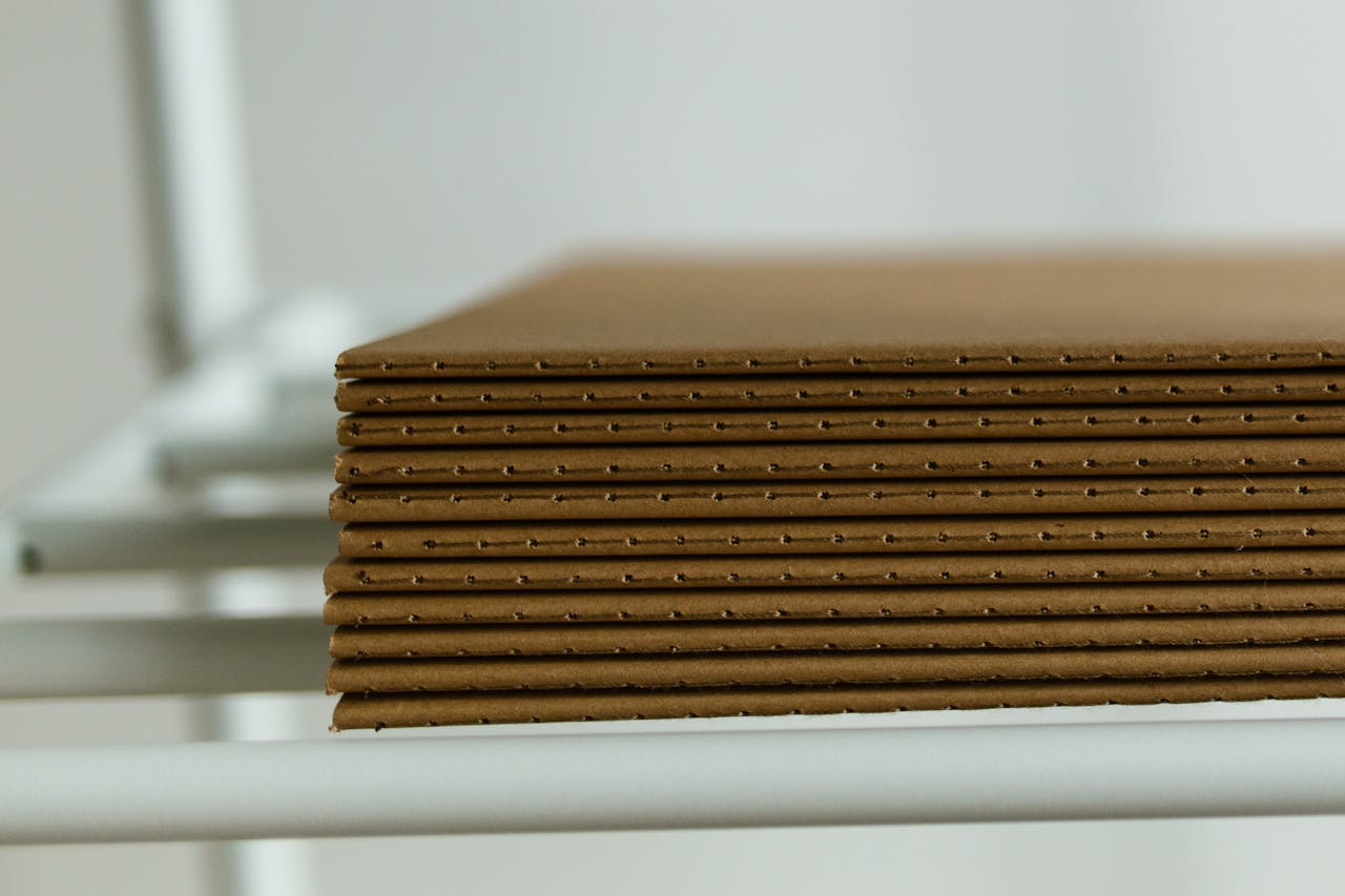 services-02 Close-up view of neatly arranged stacked cardboard sheets placed on a metal shelf, perfect for packaging concepts.